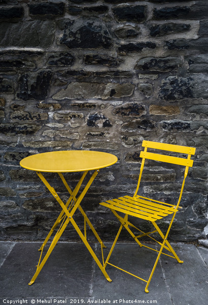 Yellow chair and table by stone wall  Picture Board by Mehul Patel