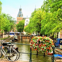 Buy canvas prints of A bicycle parked on the side of a river in Amsterd by M. J. Photography