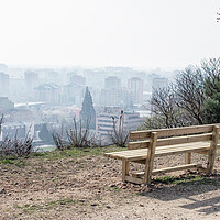 Buy canvas prints of empty wooden bench in spring park over the city by David Galindo