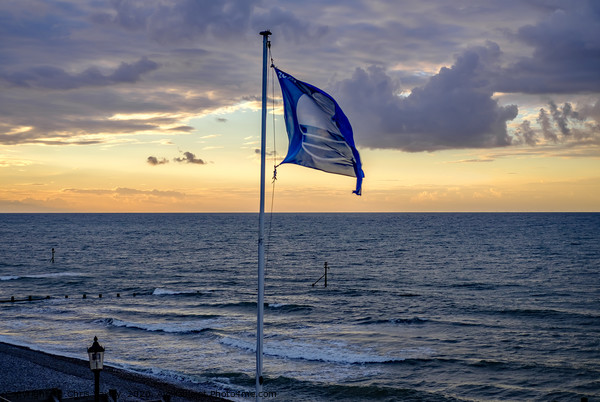Flag flying in the breeze over Sheringham beach  Picture Board by Chris Yaxley