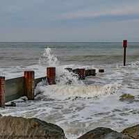 Buy canvas prints of Waves crashing over the wooden groynes at high tide on Cart Gap beach by Chris Yaxley