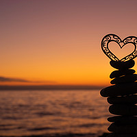 Buy canvas prints of Heart on stones on the beach at sunset. by Mariya Obidina