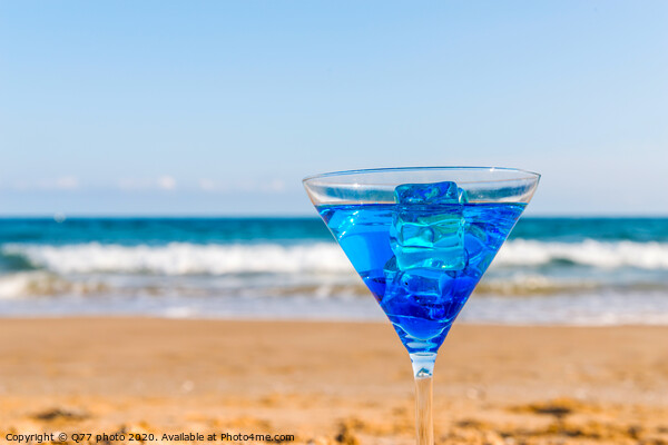 drink in a martini glass on the background of the waves affecting the sandy beach, relax on the beach, refreshing drink during the holidays Picture Board by Q77 photo