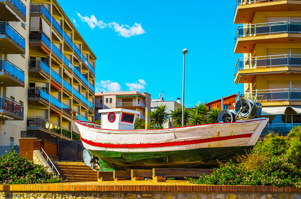 view of the promenade in the seaside town, in the middle of the roundabout old fishing boat Picture Board by Q77 photo