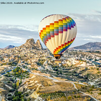 Buy canvas prints of Bright single hot air balloon drifts across highways and dwarfing old town by Michelle Silke