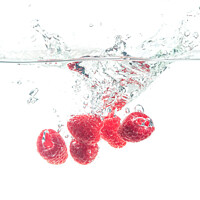 Buy canvas prints of Raspberries splashing in water on white by Przemek Iciak