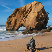 Buy canvas prints of Fisherman in Praia de Santa Cruz beach rock boulder, Portugal by Luis Pina