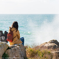 Buy canvas prints of Caucasian traveler woman looking at the waves on the sea with a yellow jacket in Peniche, Portugal by Luis Pina