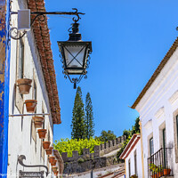 Buy canvas prints of Narrow White Street 11th Century Castle Wall  Lamp Obidos Portug by William Perry