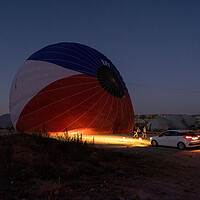 Buy canvas prints of A car parked in front of a hot air balloon with headlights on during night, preparation of a flight in Goreme national park in Cappadocia, Turkey by Arpan Bhatia