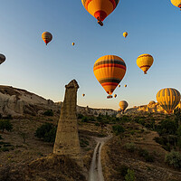 Buy canvas prints of Vertical image of bunch of colorful hot air balloon flying early morning in Cappadocia, Turkey against typical rock formation due to volcanic activity in love valley located in Goreme national park by Arpan Bhatia