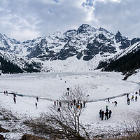 Buy canvas prints of Zakopane, Poland - May 04, 2022: Panorama of Morskie oko frozen lake covered with snowy tatra mountains with people or tourists walking on snow by Arpan Bhatia