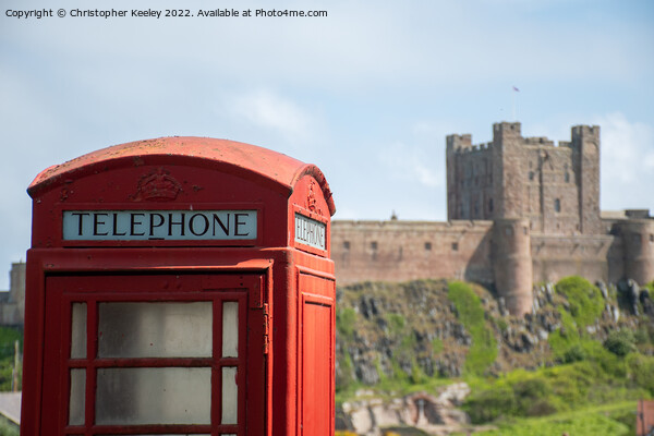 Bamburgh Castle red telephone box Picture Board by Christopher Keeley