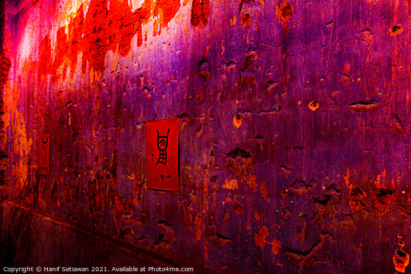 Small red poster with Chinese script on a violet wall. Picture Board by Hanif Setiawan