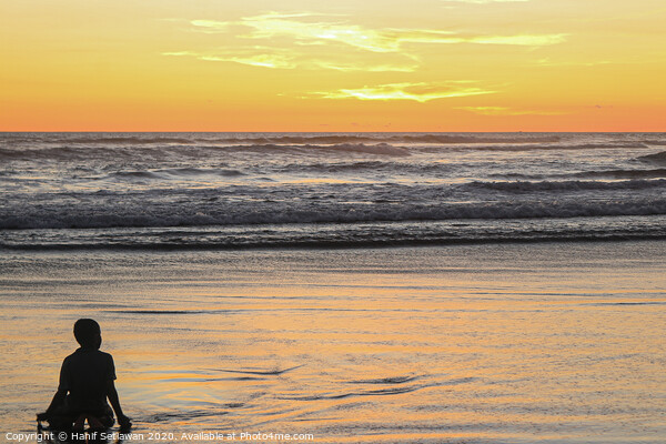 A young boy on wet sand beach at sunset. Picture Board by Hanif Setiawan