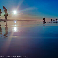 Buy canvas prints of Silhouetted people in a row on a wet sand beach. by Hanif Setiawan