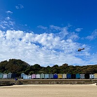 Buy canvas prints of Air ambulance taking off over beach huts at Frinton  by Paula Tracy