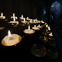 Buy canvas prints of Prayer candles shine bright in a dark cathedral by Rhys Leonard