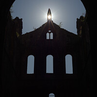 Buy canvas prints of Sun flares through opening in the peak of a ruined wall of kirkstall abbey by Rhys Leonard