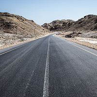 Buy canvas prints of An empty tarmac road going thru arid mountains in  by David GABIS
