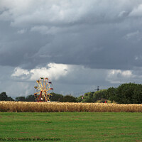 Buy canvas prints of Ferris wheel at a country show viewed from across a wheat field. Damyns Hall Aerodrome, Essex, UK. by Peter Bolton