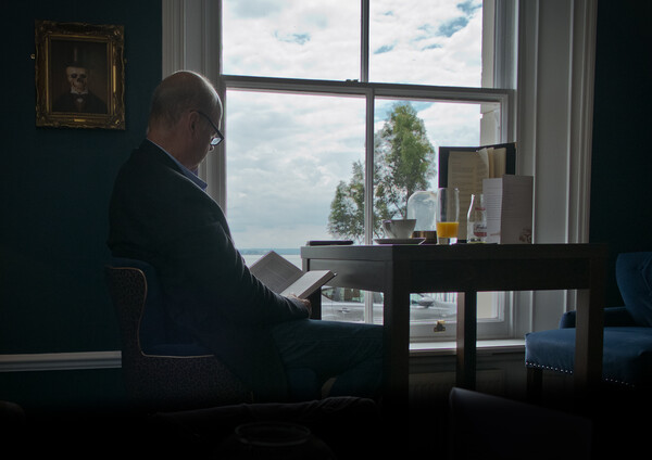 'Quiet time'. Man reading a book in front of a window. Picture Board by Peter Bolton