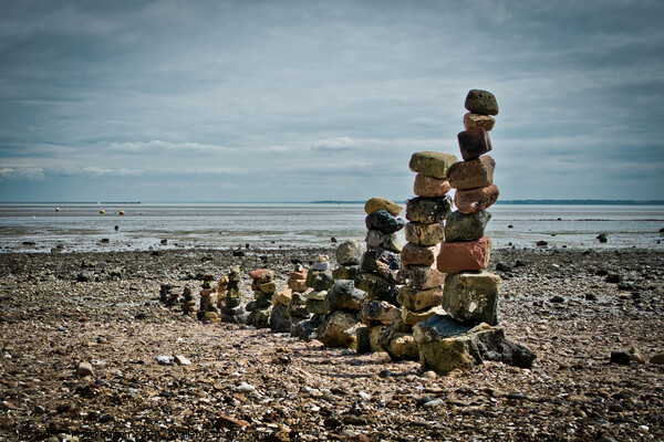 'Land art' on East Beach, Shoeburyness, Essex, UK. made from found stones, and rocks. Remains of historic victorian military buildings on the shoreline. Picture Board by Peter Bolton