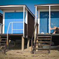 Buy canvas prints of Beach huts at Thorpe Bay, Essex, with a person sitting on the floor talking on the phone. by Peter Bolton