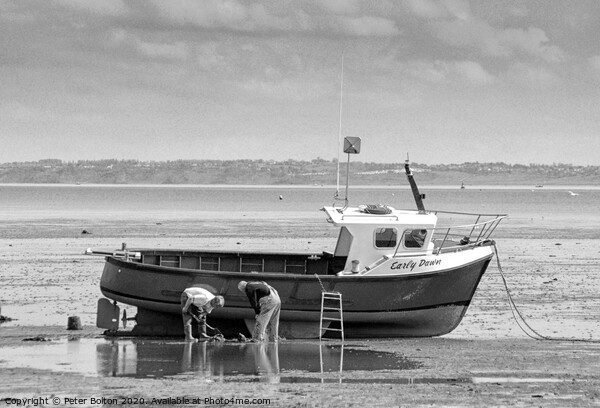 Fishermen maintain their boat at low tide at Thorpe Bay, Essex, UK. Picture Board by Peter Bolton