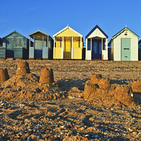 Buy canvas prints of A row of beach huts at Thorpe Bay, Essex, UK, with sandcastles on the beach in the foreground. by Peter Bolton