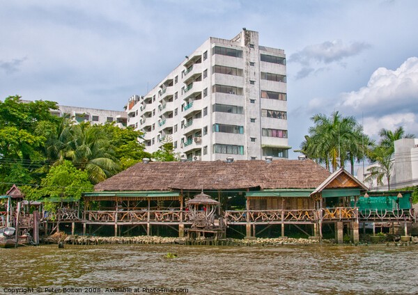 Traditional  house and modern apartment block on the Chao Phraya River, Bangkok, Thailand. Picture Board by Peter Bolton