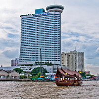 Buy canvas prints of A tourist 'junk' on The Chao Phraya River passes the Millennium Hilton Hotel in Bangkok, Thailand. by Peter Bolton
