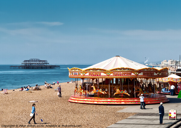 A merry-go-round on Brighton Beach on a summer day with West Pier ruins in the background. Sussex, UK. Picture Board by Peter Bolton