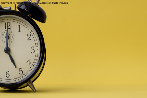 Analog alarm clock displaying five o'clock on a yellow background with copy space Picture Board by Kristof Bellens