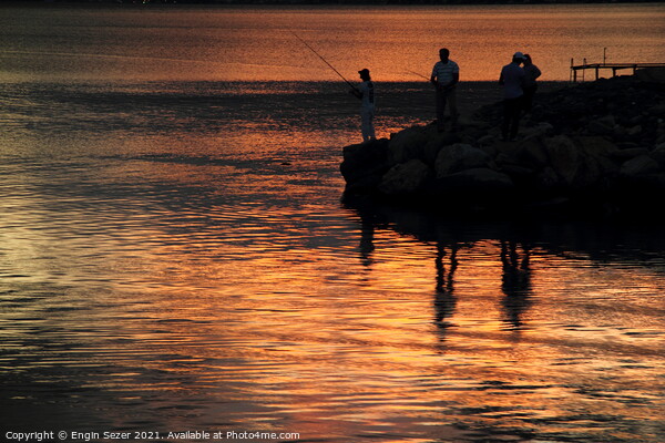 Silhouette of fishing people standing next to a bo Picture Board by Engin Sezer