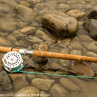 Buy canvas prints of Spey fly rod and reel resting on wet rocks beside a river. by SnapT Photography