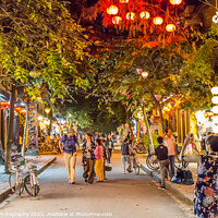 Buy canvas prints of Le loi street at night, with lanterns, trees and suit shops, Hoi An, Vietnam - January 10th, 2015 by SnapT Photography