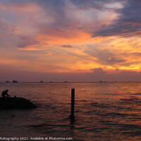 Buy canvas prints of A beautiful sunset and silhouette of a person on a rock, at Ba Keo Beach by SnapT Photography