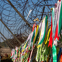 Buy canvas prints of Prayer ribbons attached to a barb wire fence at the Korean Demilitarized Zone by SnapT Photography