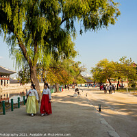 Buy canvas prints of Two women in hanboks walking beside the lake at Gyeongbokgung Palace, Seoul by SnapT Photography