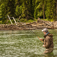 Buy canvas prints of A man hooked into a fish while fly fishing on a deep green river. by SnapT Photography