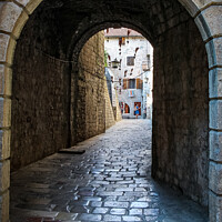 Buy canvas prints of An alley way in the old town of Kotor, with flying brooms in the background by SnapT Photography