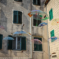Buy canvas prints of Flying umbrellas in a square in the old town of Kotor, in Montenegro by SnapT Photography