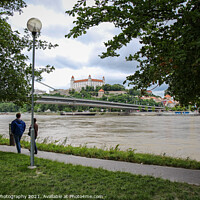 Buy canvas prints of People walking along a footpath by the River Danube with the Bratislava Castle by SnapT Photography