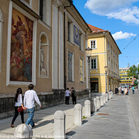 Buy canvas prints of Tourists walking past the art on the wall at Ljubljana Cathedral, Slovenia by SnapT Photography