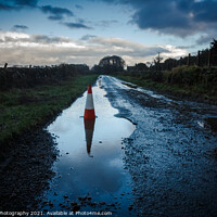 Buy canvas prints of A red traffic cone reflecting a pot hole containing a pool of water on a road by SnapT Photography