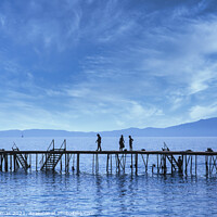 Buy canvas prints of Silhouettes on a Wooden Pier in Corfu. by Ron Thomas