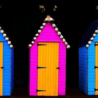 Buy canvas prints of Three brightly painted sheds with weather vanes on top by Peter Wiseman