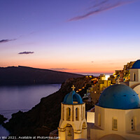 Buy canvas prints of Blue domed churches and traditional white houses facing Aegean Sea with warm sunset light in Oia, Santorini, Greece by Chun Ju Wu