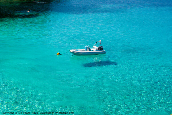 Boat floating on crystal clear water Picture Board by Nic Croad